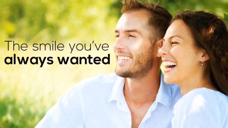 a couple smiling with greenery in the background, the wording" the smile you've always wanted on the image.