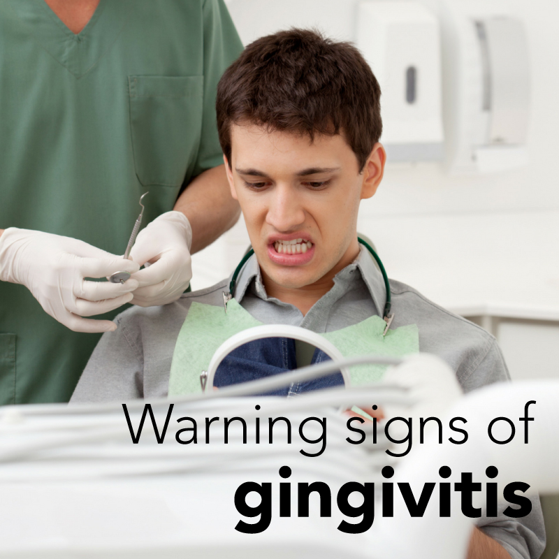 A young man in a dentist's chair looks uncomfortable as a dentist prepares to examine his teeth. The image has the text "Warning signs of gingivitis" overlaid on it.