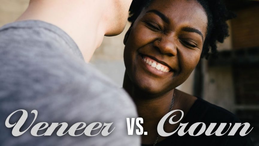 a joyful moment between two people. The woman, with short curly hair and a nose piercing, is smiling widely and leaning towards her companion. The other person, seen from behind, is wearing a gray shirt. At the bottom of the image, the text "Veneer vs. Crown" is written in a stylish font.