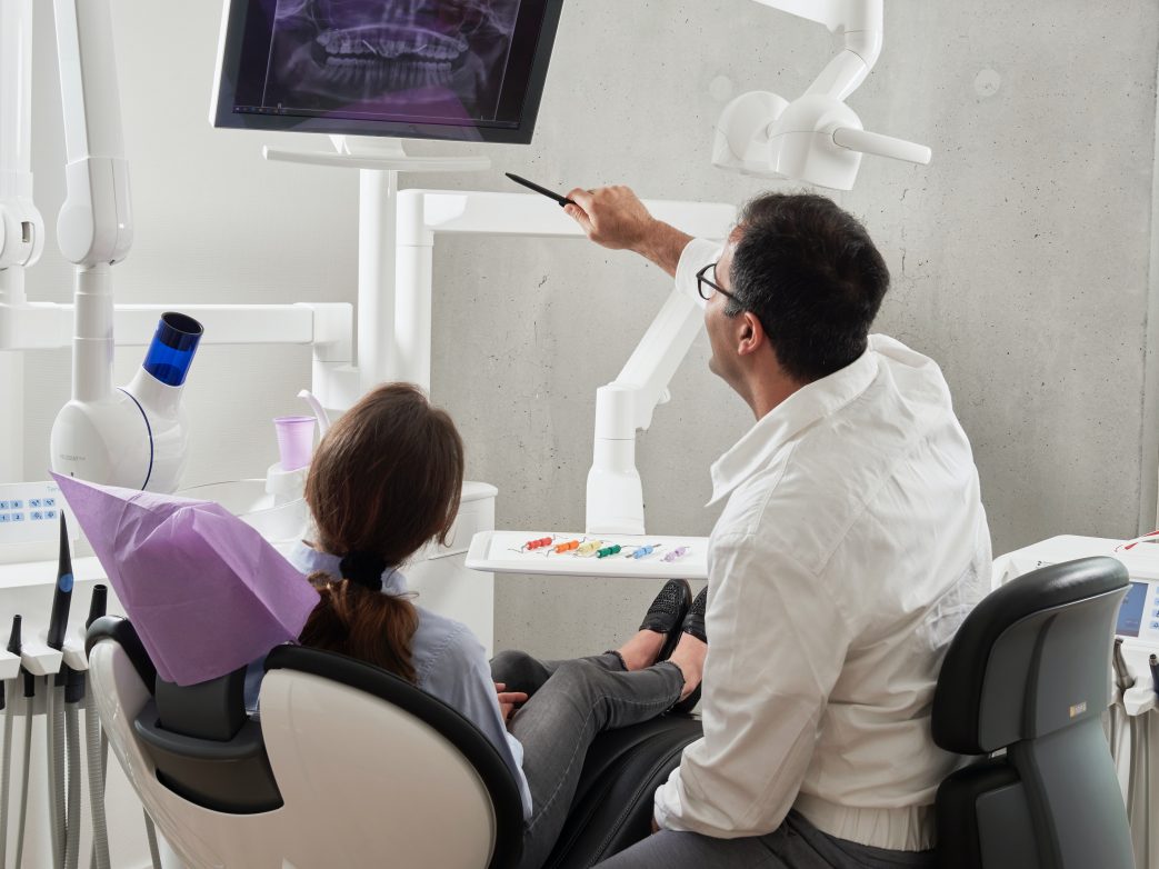 Male dentist reviewing x-ray with female patient.